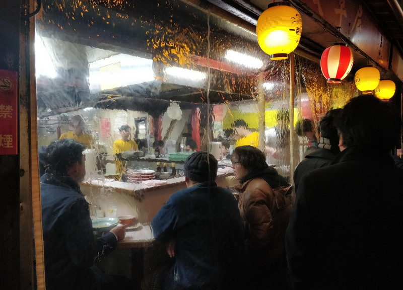 Some friends eating and drinking together, at a bar in piss alley, Shinjuku Tokyo,